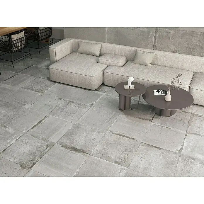 Feinsteinzeugfliese Bond Ash - 60 x 60 cm, Grau, Matt - Ein stilvolles Wohnzimmer mit großen, quadratischen Bodenfliesen in Grau, die einen modernen und industriellen Look erzeugen.