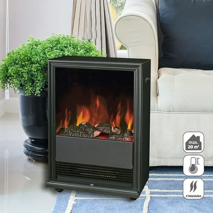 Voltomat HEATING Elektrischer Kamin - 2.000 W, Schwarz, 27,5 x 43 x 62,5 cm - Bild eines elektrischen Kaminofens in Schwarz neben einer Couch und einer Pflanze. Der Kamin sorgt für eine gemütliche Atmosphäre im Raum.