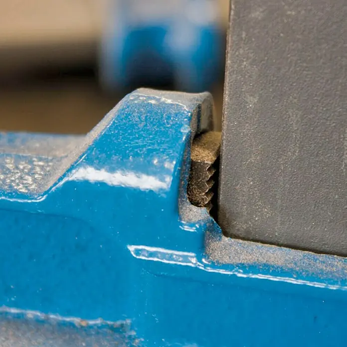 Piher Sargento R-40 - Anchura de sujeción: 400 mm, Fuerza de tensión: 1.000 N, Apertura máxima: 150 mm - Detalle de un tornillo de banco azul sujetando una pieza gris, mostrando la construcción robusta ideal para tareas pesadas.