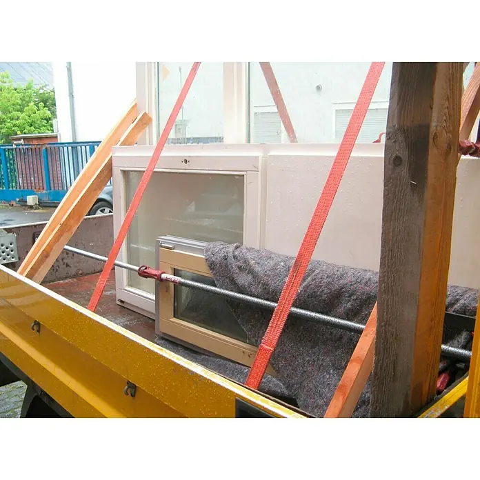 Piher Puntal regulable P2 - Anchura de expansión: 95 cm - 170 cm, Rojo/Negro - Ventanas y materiales de construcción transportados en un camión amarillo con cintas rojas. Los soportes de madera estabilizan la carga.
