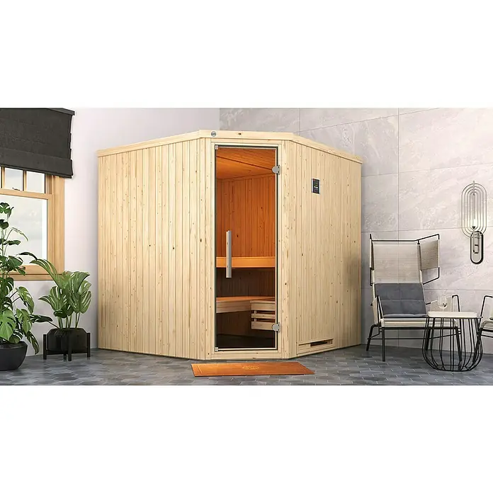 Weka Elementsauna Varberg Typ 1 - 7,5 kW Bio-Ofen mit externer Steuerung, L x B x H: 194 x 194 x 199 cm - Eine helle Holzsauna mit Glastür steht im Raum, neben einem modernen Stuhl und einem Beistelltisch. Die Sauna lädt zum Entspannen ein.