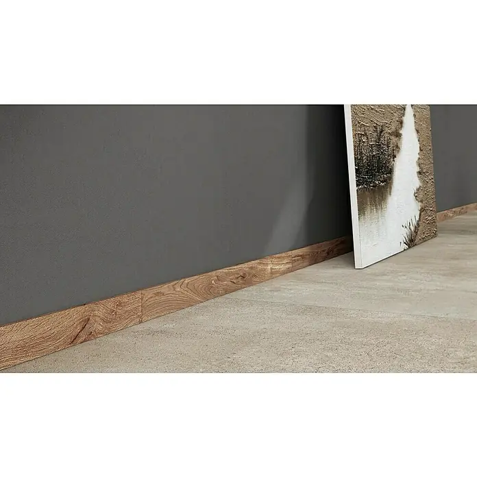 Atlas Concorde Solution Fable Sockelfliese Honey - 7,2 x 90 cm, Braun - Ein Wandpaneel mit Holzstruktur trifft auf einen grauen Untergrund, daneben ein Kunstwerk, das ein natürliches, ruhiges Ambiente ausstrahlt.