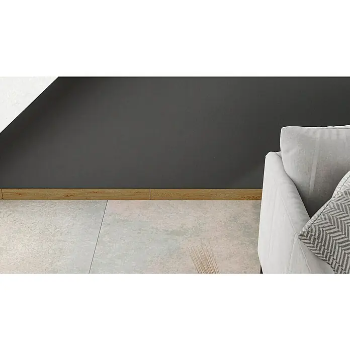 Atlas Concorde Solution Sockelfliese Twist Rovere - 7,2 x 90 cm, Beige, Matt - Ein heller Raum mit Fliesenboden, dunkler Wand und hölzernen Fußleisten, neben einem Teil eines weißen Sofas mit Kissen.
