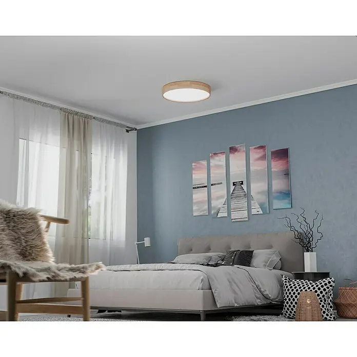 Globo LED-Deckenleuchte rund RAINER - 24 W, Ø x H: 40 x 10,5 cm, Holz, Mehrfarbig - Deckenleuchte mit runder Holzfassung in einem modernen Schlafzimmer mit Kunst, Bett und Stuhl. Das Licht erhellt den Raum sanft.