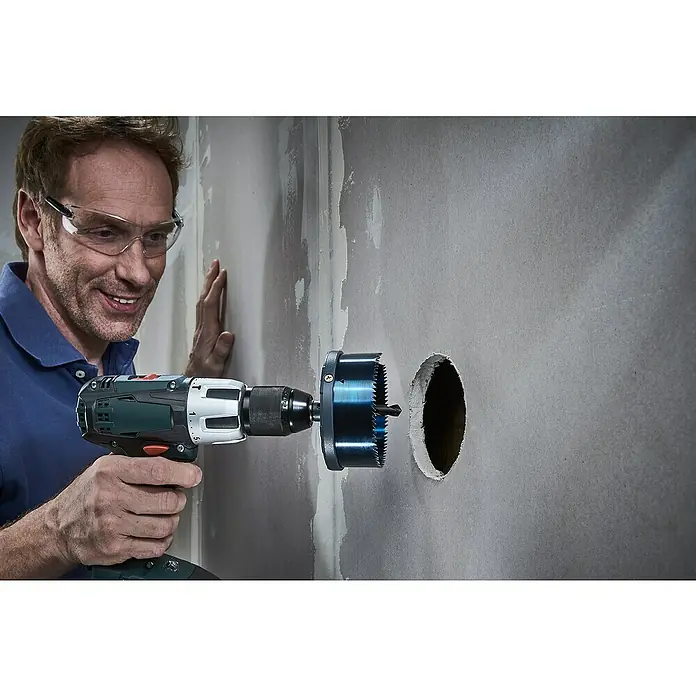 Wolfcraft Mehrkranzlochsäge - 5 -tlg., Arbeitsdurchmesser: 60 mm - 95 mm, Schnitttiefe: 33 mm - Mann bohrt mit einer Lochsäge ein Loch in eine Wand. Der Bohrer ist gut sichtbar und das Loch in der Wand ist sauber und rund.
