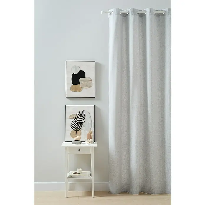 Visillo para ventana Gorgina - An x Al: 140 x 260 cm, 100% poliéster, Gris - Una foto vertical muestra una cortina gris que cuelga de una barra, ocultando parcialmente una escena con una mesa y dos cuadros enmarcados al fondo.