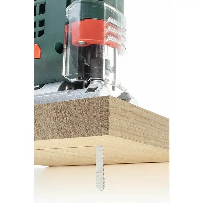 Wolfcraft Stichsägeblatt - Spanplatten, T-Schaft, Schnitttiefe: 3 mm - 30 mm, 2 Stk. - Detailaufnahme einer grünen Oberfräse beim Bearbeiten eines Holzstücks, wobei das Fräsmesser sichtbar ist.