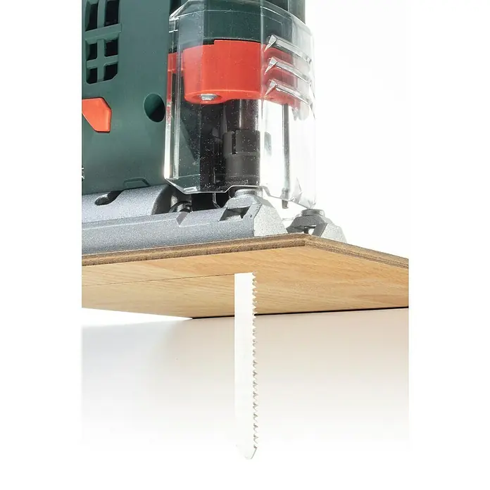 Wolfcraft Stichsägeblatt - Spanplatten, T-Schaft, Schnitttiefe: 3 mm - 30 mm, 2 Stk. - Nahaufnahme einer Stichsäge beim Schneiden eines Holzstücks, wobei das Sägeblatt deutlich sichtbar ist.