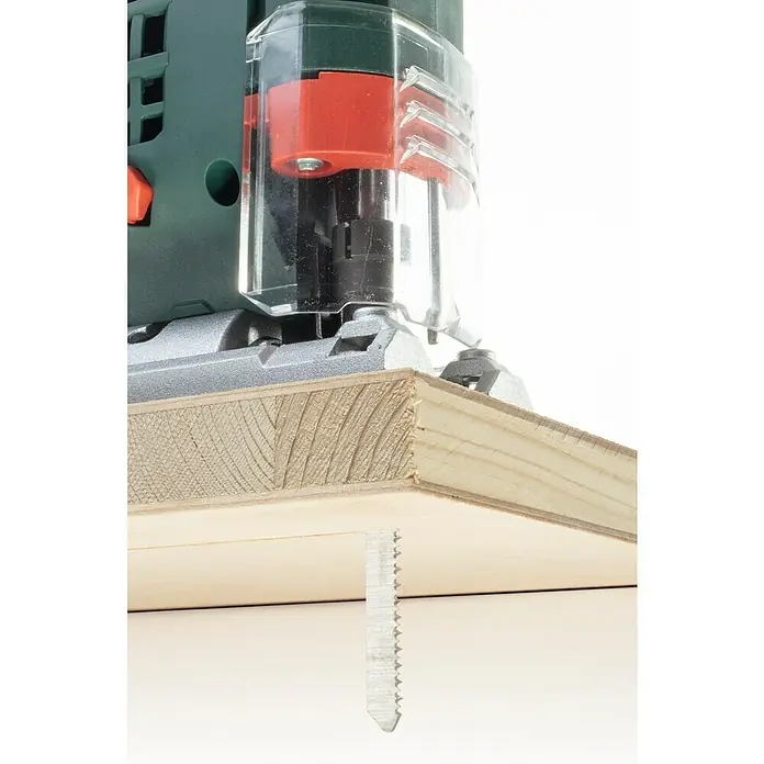 Wolfcraft Stichsägeblatt - Spanplatten, T-Schaft, Schnitttiefe: 3 mm - 30 mm, 2 Stk. - Bild einer Stichsäge in Aktion, die durch ein Holzbrett schneidet. Die Säge ist grün und hat einen transparenten Schutz.