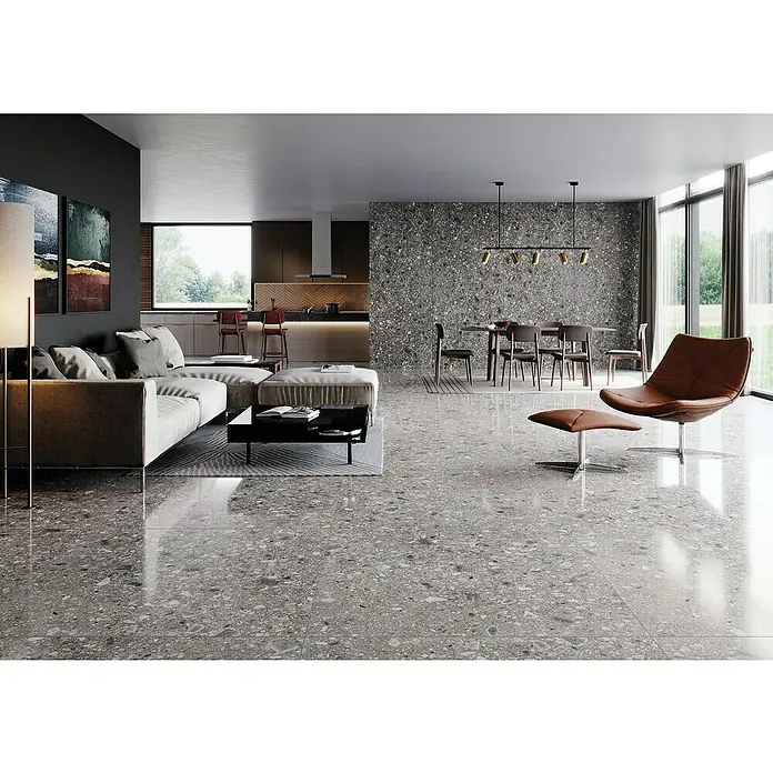 Feinsteinzeugfliese Terrazzo Ceppo59,7 x 59,7 cm, Graphit, Matt - Helles Wohnzimmer mit stilvollem Sofa, Sesseln und großflächigen Fliesen. Die grauen Fliesen dominieren und verleihen dem Raum Eleganz.