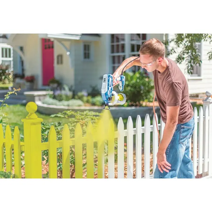 Graco Magnum Sistema de pulverización de pintura Compact A5DS - Velocidad de trabajo: 6 m²/min - Un hombre está pintando una valla de jardín con un pulverizador de pintura. Ideal para aplicaciones rápidas y uniformes en exteriores.