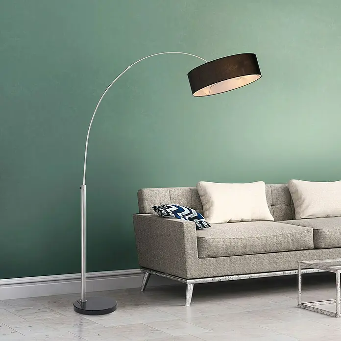 Just Light Stehleuchte Petro - Höhe: 200 cm, Stahl, Schwarz, E27 - Elegante Stehlampe mit schwarzem Lampenschirm und gebogenem Chromständer, die stilvoll neben einem grauen Sofa im Wohnzimmer steht.