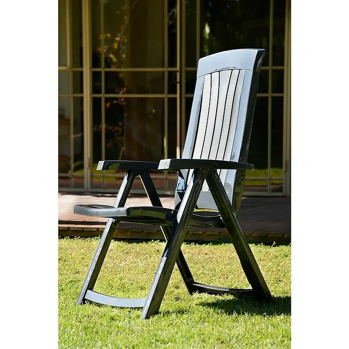 Keter Sillón de jardín Corsica - 61 x 70 x 110 cm, Grafito, Polipropileno - Una elegante silla de jardín de plástico negro con reposabrazos está sentada en un césped verde, invitando a relajarse. Ideal para momentos de paz al aire libre.