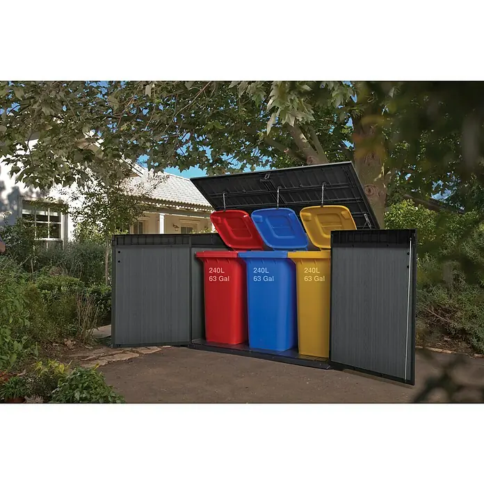Keter Truhe Cortina Mega - Außenmaß inkl. Dachüberstand (B x T): 191 x 109 cm, Kunststoff, Anthrazit/Schwarz - Ein Mülltonnenschrank in Grau mit drei farbigen Mülltonnen (rot, blau, gelb) im Garten, der die Mülltrennung erleichtert.