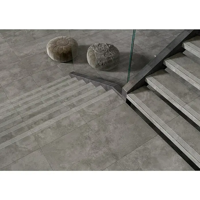 Queens Stufen- & Abdeckplatte - 29,8 x 59,8 cm, Grau, Matt - Graue Fliesen auf Boden und Treppe mit zwei Sitzkissen und Glasgeländer. Perfekt für moderne Innenräume, zeitlose Eleganz und Stil.
