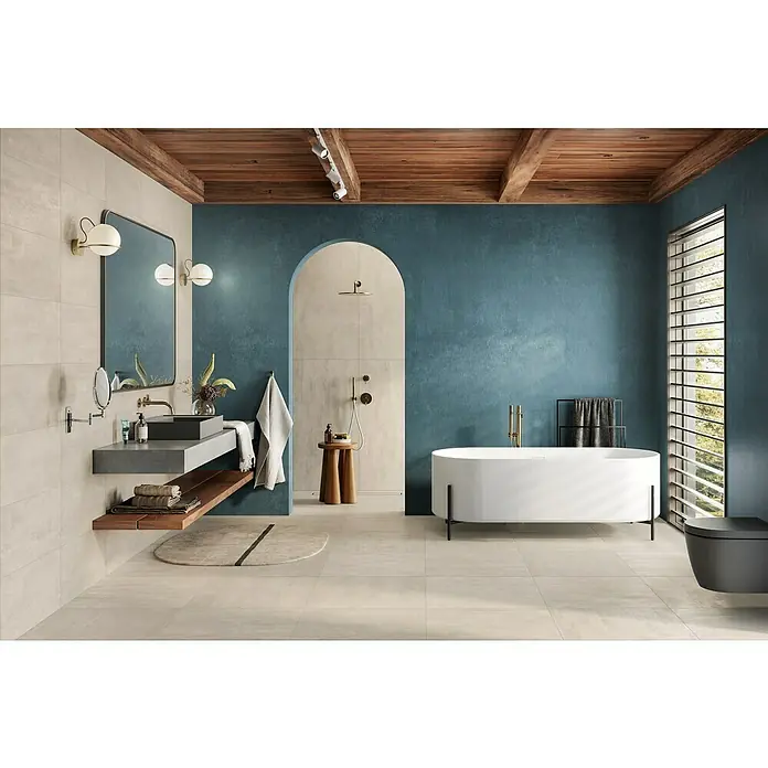 Atlas Concorde Solution Yorkshire Feinsteinzeugfliese Almond - 60 x 60 cm, Beige, Matt - Elegantes Badezimmer mit freistehender Badewanne, modernem Waschbecken und stilvoller Beleuchtung unter einer Holzdecke für ein luxuriöses Ambiente.