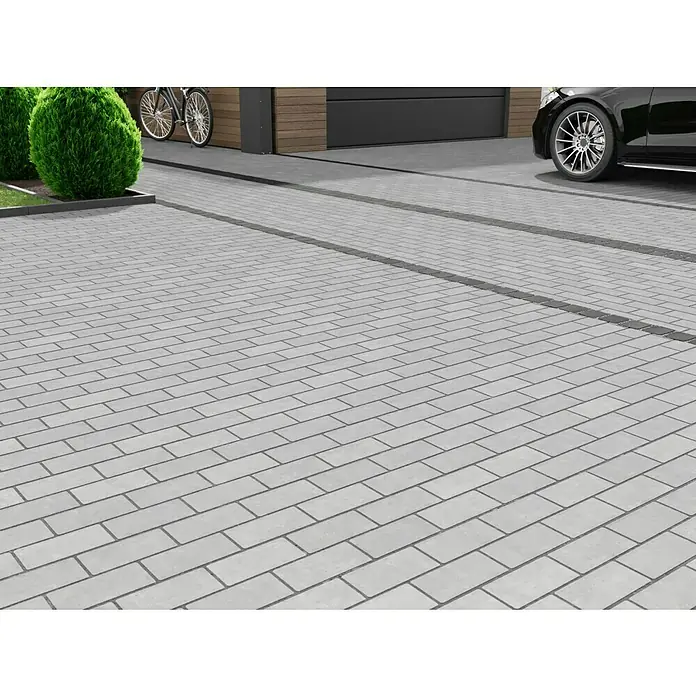 EHL Pflasterstein Drän - Grau, 20 x 10 x 8 cm, Rechteckig - Pflastersteine in Grau verlegt auf einer Einfahrt mit einem Auto und Fahrrädern im Hintergrund.