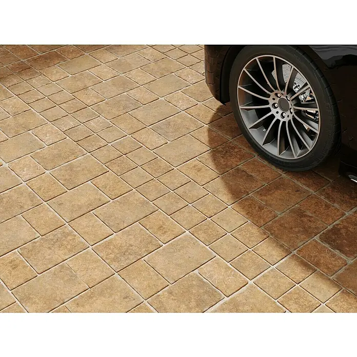 Diephaus Pflasterstein Austin - Sandstein, 28 x 21 x 7 cm, Rechteckig - Nahaufnahme eines Pflastersteins in einem warmen Farbton neben dem Rad eines Autos, das die rustikale und dauerhafte Beschaffenheit des Steins hervorhebt.