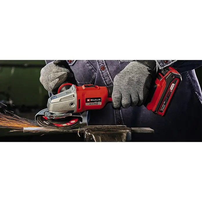 Einhell Schnellspannmutter - Passend für: Einhell Winkelschleifer mit M14 Aufnahme - Einhell Akku-Winkelschleifer AXXIO im Einsatz mit Arbeitshandschuhen. Funken fliegen beim Schleifen eines Metallstücks in einem Schraubstock.