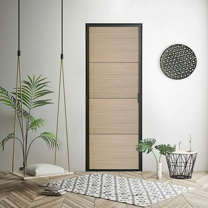 Kit atelier Drehtür Loft Holz District - 880 x 2.005 mm, Links - Eine moderne, holzfarbene Innentür mit schwarzem Rahmen, die sich nahtlos in ein stilvolles Interieur mit hellen Wänden und Holzboden einfügt.