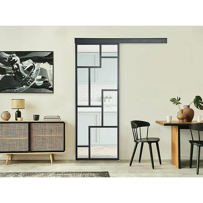 Kit atelier Glasschiebetür Loft Architekt - 930 x 2.128 mm, Einscheibensicherheitsglas (ESG) - Ein modernes Interieur mit einer auffälligen Schiebetür mit geometrischem Glasdesign, die den Raum optisch erweitert und strukturiert.