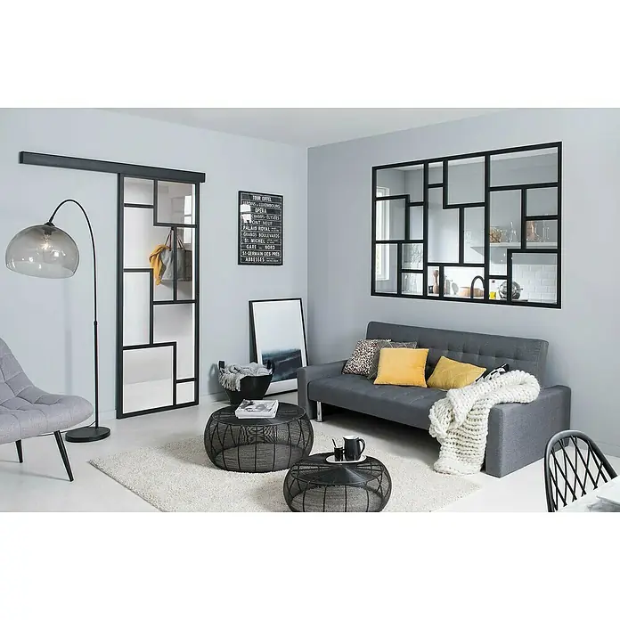 Kit atelier Glastrennwand Loft Architekt - 1.832 x 1.200 mm, Einscheibensicherheitsglas (ESG) - Ein stilvolles Wohnzimmer mit einem grauen Sofa, Couchtischen und einem Spiegel mit schwarzem Rahmen, der dem Raum einen modernen Touch verleiht.