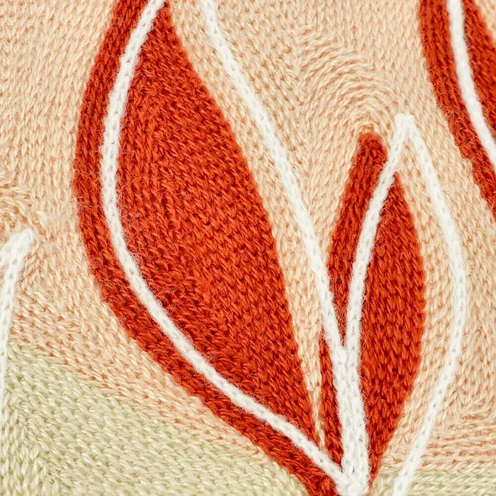 Kissen Irma - Muted Clay, 45 x 45 cm, 70 % Baumwolle, 30 % Acryl - Detailaufnahme eines gestickten Blättermotivs in Orange, Weiß und Beige. Die Stickerei verleiht jedem Raum eine warme und natürliche Note.