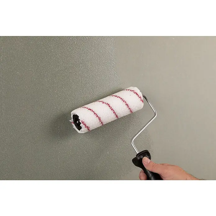 Knauf Tiefengrund - 5 l - Nahaufnahme einer Person, die eine Wand mit einem Farbroller mit weißem Bezug und roten Streifen streicht.
