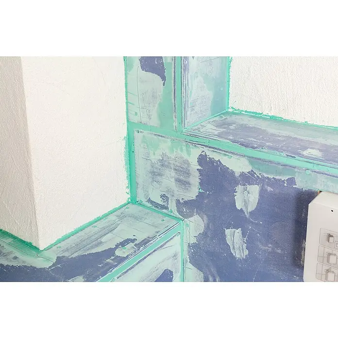 Knauf Gipskartonplatte Diamant GKFI2.000 x 1.250 x 12,5 mm, Imprägniert - Nahaufnahme einer Trockenbauwand mit grünen Farbtupfern, die Details und Textur des Renovierungsprojekts hervorhebt.