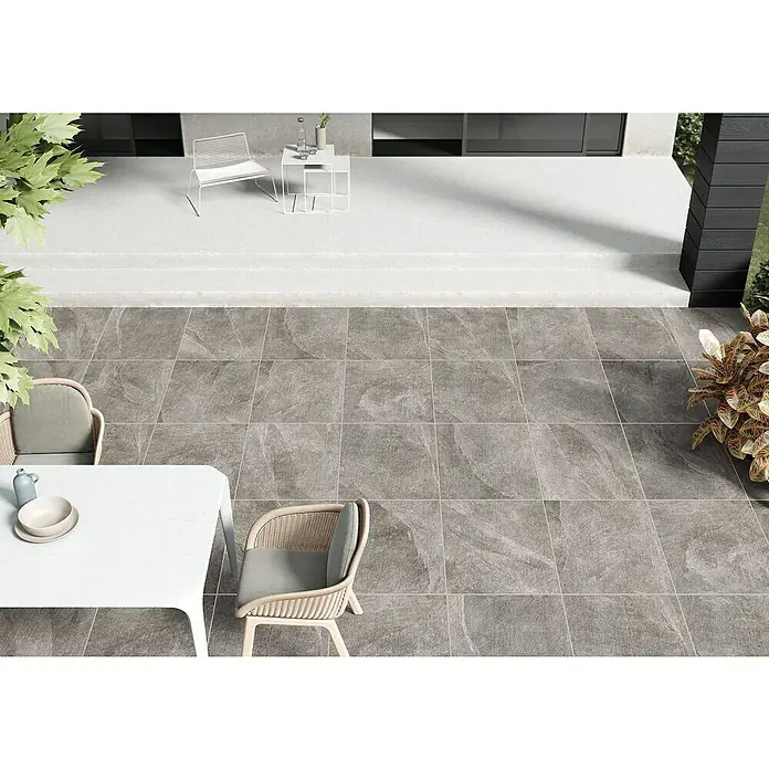 Terrassenfliese Click and Go Ardesia Grey - 60 x 60 cm, Grau, Matt - Graue Bodenfliesen auf einer Terrasse mit weißen Gartenmöbeln. Die Fliesen haben eine natürliche Steinoptik und verleihen der Terrasse einen modernen Touch.