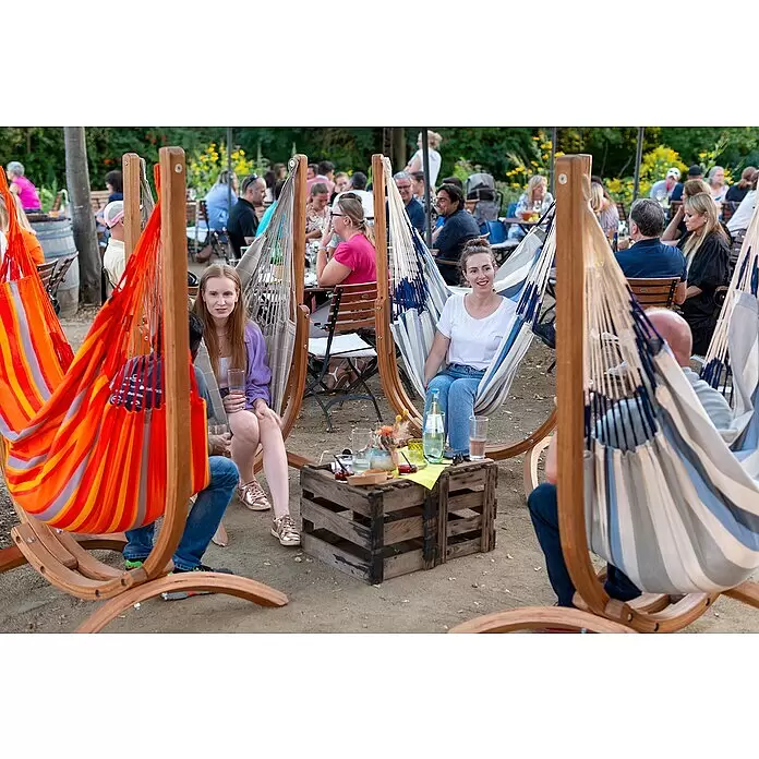 La Siesta Hängematten-Set Udine - L x B x H: 180 x 115 x 163 cm, Rot/Grau/Orange - Personen entspannen in gestreiften Stoffhängematten mit geschwungenen Holzständern im Freien.