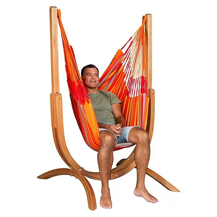 La Siesta Hängematten-Set Udine - L x B x H: 180 x 115 x 163 cm, Rot/Grau/Orange - Mann entspannt sich in einem bunten gestreiften Hängesessel aus Stoff mit Naturholzständer.