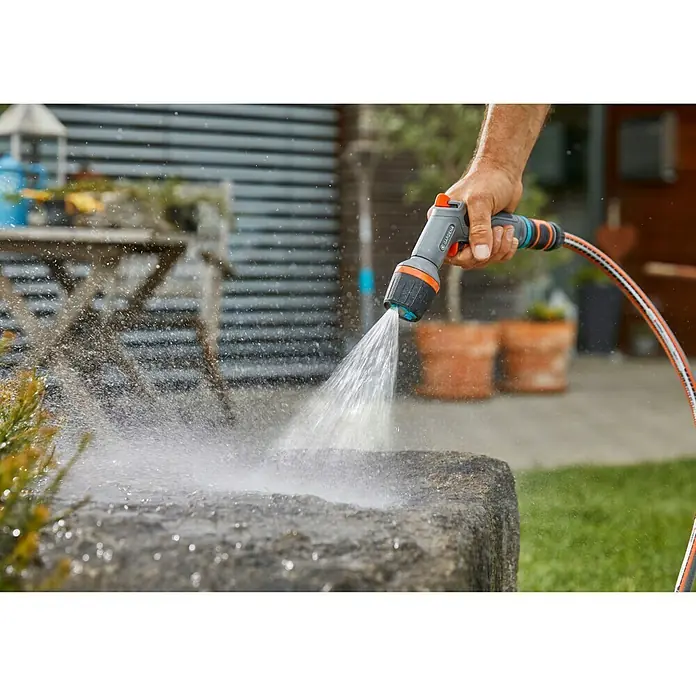 Gardena Reinigungsspritze Comfort ecoPulse - Kunststoff - Nahaufnahme einer Gardena-Gartenspritze, die Wasser auf eine Steinoberfläche sprüht, ideal für Gartenbewässerung und Reinigungsarbeiten im Freien.