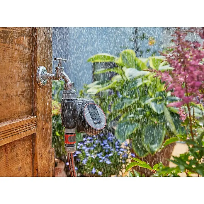 Gardena Bewässerungscomputer Flex - Bewässerungsdauer: 1 s - 99 min - Nahaufnahme eines Wasserhahns mit einem Bewässerungscomputer von Gardena im Garten, der mit Wasser bespritzt wird.