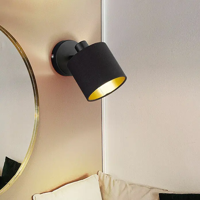 Reality Leuchten Tommy Deckenstrahler - 28 W, Höhe: 19 cm, Schwarz, E14, 1 Stk. - Schwarze Wandleuchte mit goldenem Inneren montiert an einer Wand neben einem Spiegel und einem Kissen.