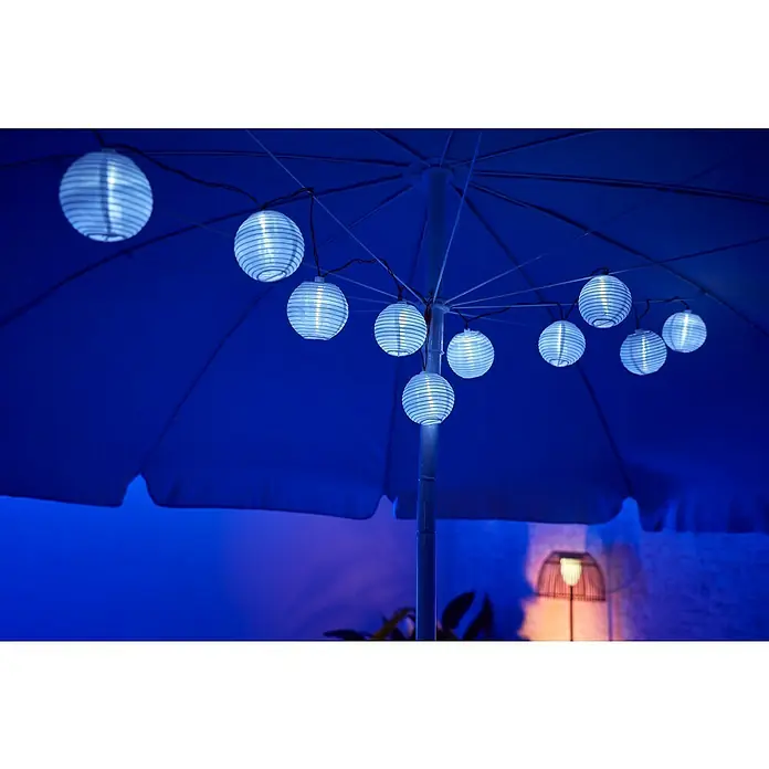 BAUHAUS Solar-Lichterkette MinilampionsLänge: 3,8 m, LED, Leuchtdauer: 8 h, Weiß - Nahaufnahme einer blauen Sonnenschirmdekoration mit Lampions, die eine stimmungsvolle Atmosphäre erzeugen.