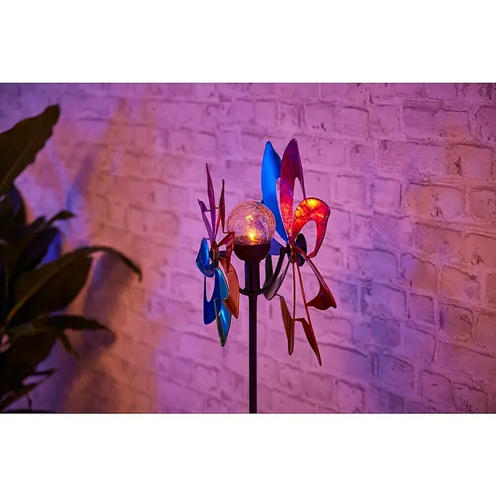 BAUHAUS Solar-Erdspieß WINDSPINNER - 0,06 W, L x B x H: 16 x 38,5 x 137 cm, Bunt, IP44, 1 lm - Windspiel mit Solarleuchte vor einer Ziegelwand. Die farbigen Elemente des Windspiels drehen sich um eine leuchtende Kugel.