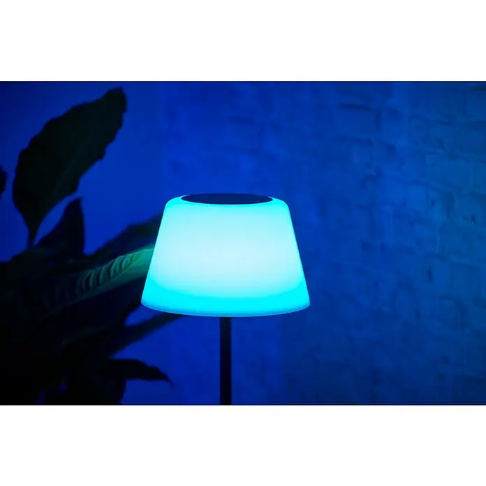 BAUHAUS Solar-Stehleuchte - 5,8 W, L x B x H: 27,5 x 27,5 x 105,5 cm, Schwarz/Weiß, IP44 - Nahaufnahme einer modernen Tischleuchte mit blauem Licht, die ein angenehmes Ambiente schafft. Die Leuchte steht vor einer strukturierten Wand.