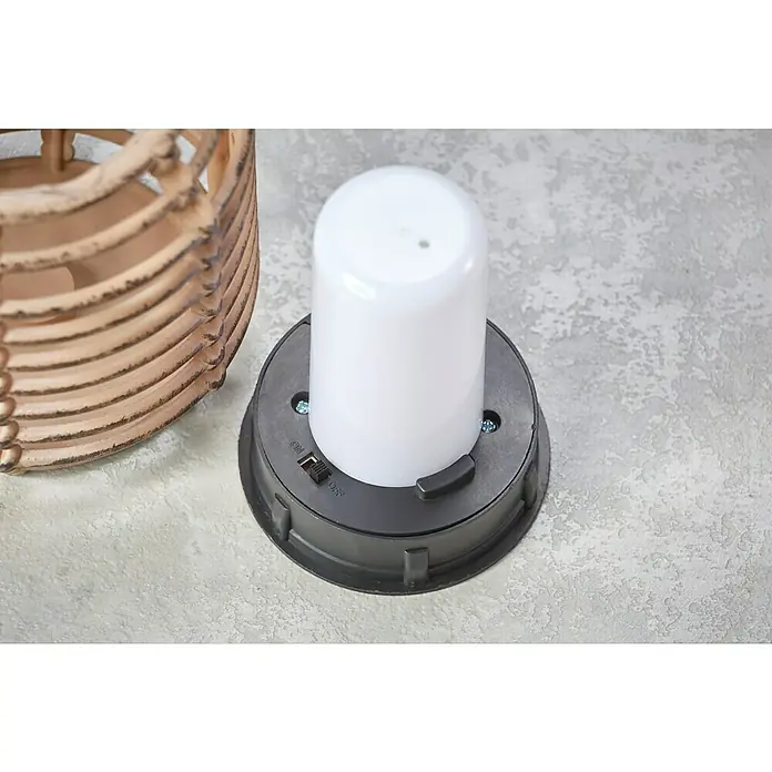 BAUHAUS Solar-Tischleuchte - Rattan, IP44 - Nahaufnahme einer Solarleuchte mit einem weißen, zylindrischen LED-Licht und einem schwarzen Sockel mit einem Ein-/Ausschalter.