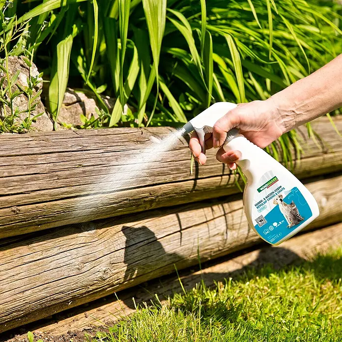 Windhager Hunde- & Katzen-Schreck - 500 ml - Eine Person sprüht Windhager Hunde & Katzen Stopp Repellent Spray auf ein Holzbett im Garten.