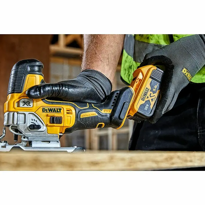 DeWalt XR 18V Akku-Pendelhubstichsäge DCS335N-XJ - 18 V, Ohne Akku, Leerlaufhubzahl: 1.000 /min - 3.200 /min - Akkubetriebene DeWalt Stichsäge mit gelbem und schwarzem Gehäuse in Aktion, wird von einer Person mit Arbeitshandschuhen bedient.
