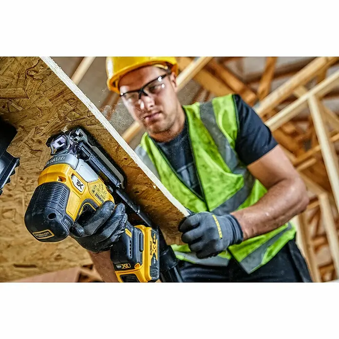 DeWalt XR 18V Akku-Pendelhubstichsäge DCS335N-XJ - 18 V, Ohne Akku, Leerlaufhubzahl: 1.000 /min - 3.200 /min - Ein Bauarbeiter befestigt OSB-Platten mit einem gelben Akku-Nagler von Dewalt.