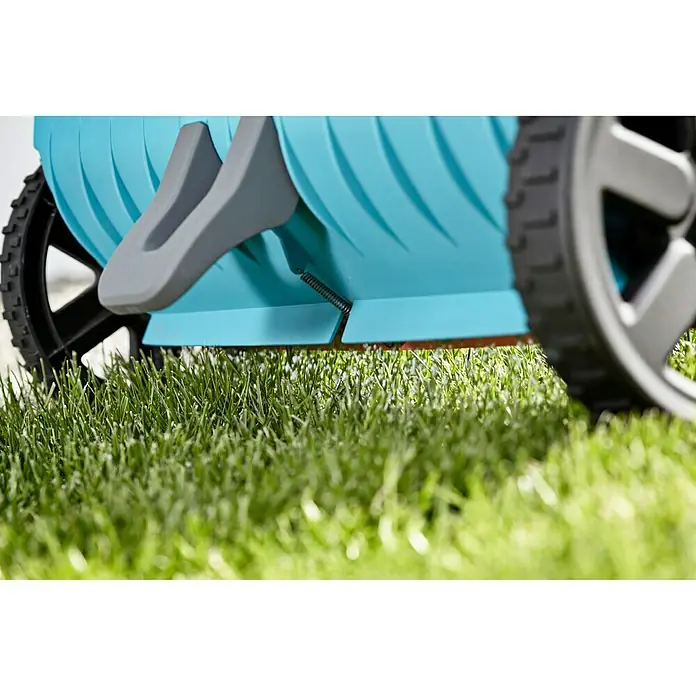 Gardena Streuwagen L - Streubreite: 45 cm, 12,5 l - Detailaufnahme eines Gardena-Rasenlüfters mit blauen Lamellen, grauen Griffen und schwarzen Rädern auf grünem Rasen.
