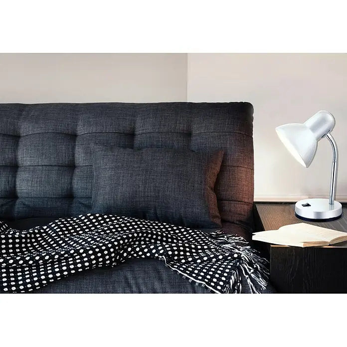 Globo Lámpara de sobremesa Basic - L x An x Al: 21,5 x 21,5 x 35 cm, 40 W, Plateado, E27 - La imagen muestra una lámpara de noche junto a un libro sobre una mesita de noche, con un cabecero gris y una manta de lunares de fondo.