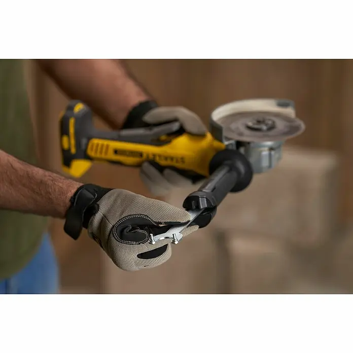 Stanley FatMax Akku-Winkelschleifer SFMCG700B-XJ - Ohne Akku, Durchmesser Scheibe: 125 mm - Nahaufnahme eines Stanley-Winkelschleifers in Aktion, der von einer Person mit Schutzhandschuhen bedient wird.