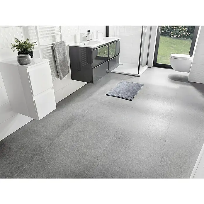 Camargue Badheizkörper Plus - B x H: 500 x 1.750 mm - Badezimmer mit grauem Fliesenboden, weißem Waschtisch und dunklem Unterschrank. Ein grauer Teppich liegt auf den Fliesen.