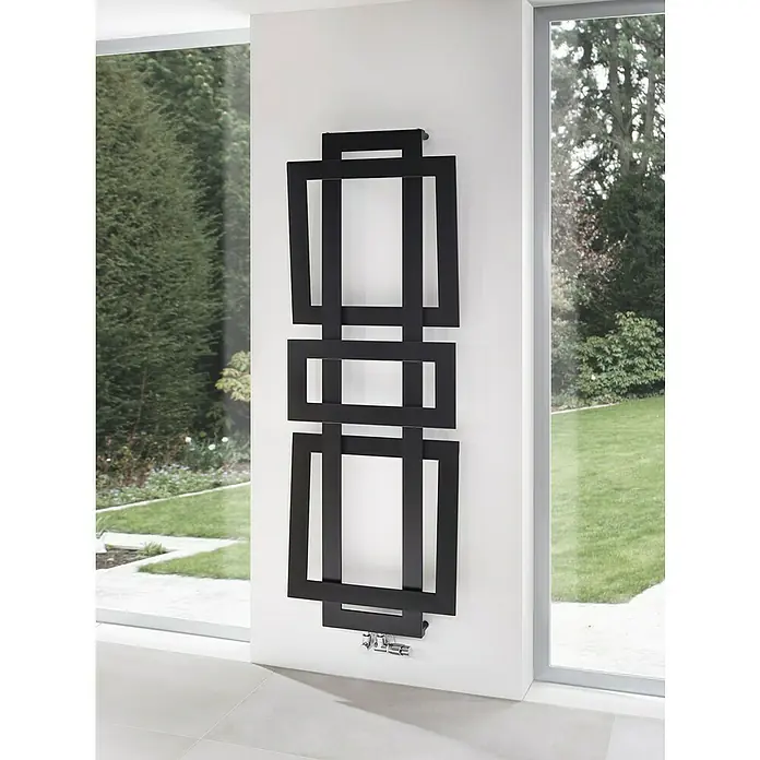 Szagato Designheizkörper Art II - B x H: 600 x 1.800 mm, Wärmeleistung bei Vorlauftemperatur von 75 °C (D: 50): 1.019 W, Schwarz - Ein moderner, schwarzer Designheizkörper mit geometrischen Formen hängt an einer weißen Wand in einem hellen Raum.