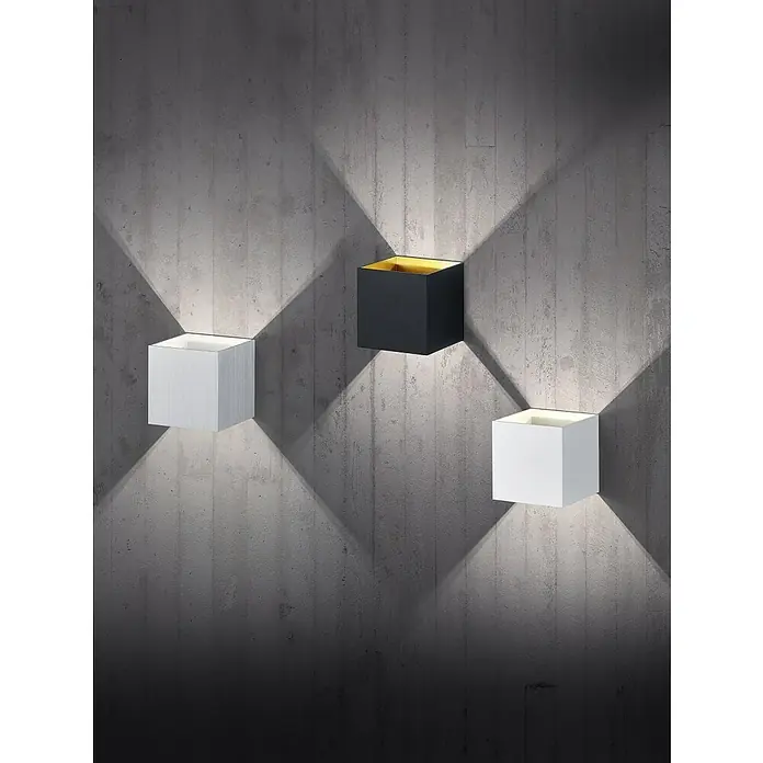Trio Lighting Aplique de pared Louis - 4,2 W, L x An x Al: 10 x 10 x 10 cm, Blanco - Apliques de pared en forma de cubo: uno blanco, uno negro con interior dorado y una tercera luz blanca sobre una pared de hormigón.