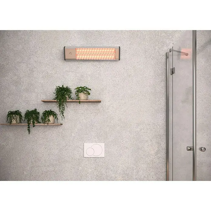 Voltomat HEATING Quarzheizstrahler - 14 x 60 x 13 cm, 1.200 W, Chrom - Nahaufnahme eines an der Wand montierten Heizstrahlers im Badezimmer, neben Pflanzenregalen und einer Dusche für ein warmes Ambiente.
