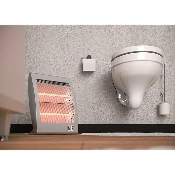 Voltomat HEATING Quarzheizstrahler - 30 x 14 x 33,5 cm, 800 W, Grau - Das Bild zeigt eine Nahaufnahme einer Heizung im Badezimmer neben einer Toilette, die eine gemütliche Atmosphäre erzeugt.